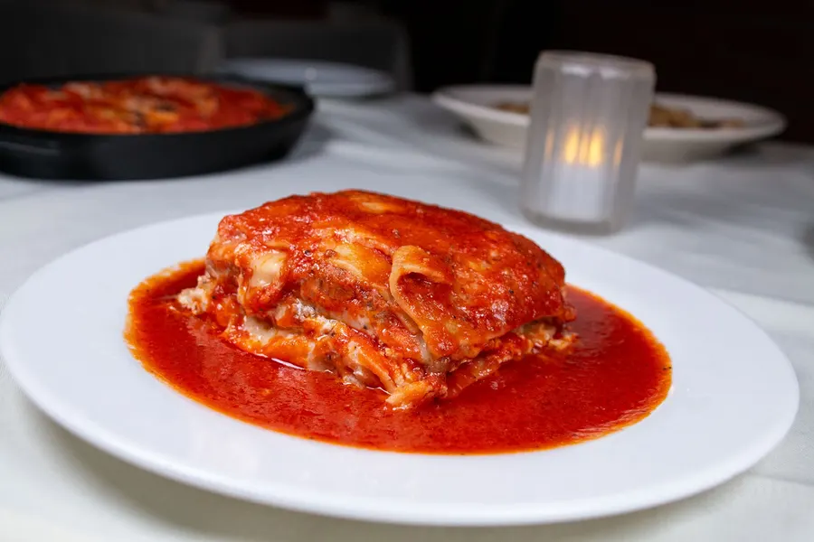 Baked lasagna in red sauce on a white plate