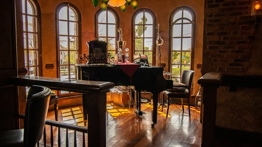 Dining area with piano and tall arched windows
